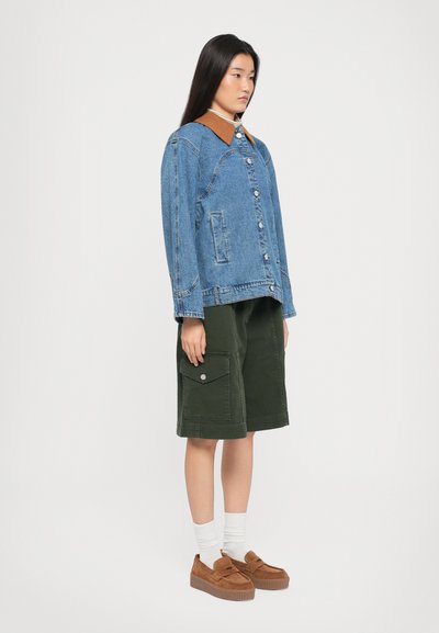 Τζάκετ τζιν με καφέ γιακά, πράσινες cargo βερμούδες με πλάγιες τσέπες, λευκές κάλτσες και καφέ πλατφόρμες. Απλή, καθημερινή εμφάνιση.