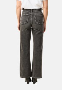 Szare dżinsy z wysokim stanem o prostych nogawkach, wyposażone w tylne kieszenie z wzorem szycia w zygzak oraz subtelną fakturą.