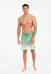 Groene gradient zwembroek met een gestructureerd patroon, trekkoord in de taille en een effen witte zoom. Het materiaal lijkt lichtgewicht en klaar voor gebruik in het water.