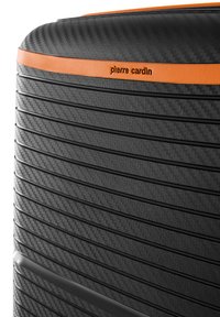Valigia nera con ruote, caratterizzata da un motivo in fibra di carbonio testurizzato, striscia di accento arancione, scanalature verticali e dettagli del logo.