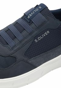 Tumedas sinises spordijalatsis on sujuvate ja tekstureeritud materjalide kombinatsioon, elastsed rihmad ja valge tald, millel on bränd "S. OLIVER" graveering.
