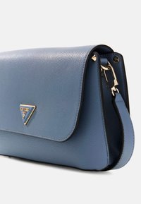 Borsa in pelle blu con finitura testurizzata, dotata di chiusura a pattina e emblematico logo in tonalità oro. Include una tracolla rimovibile e dettagli in metallo.