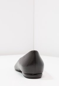 Ballerine in pelle nera con punta arrotondata, design elegante, texture liscia e tacco basso visibile dalla vista posteriore.