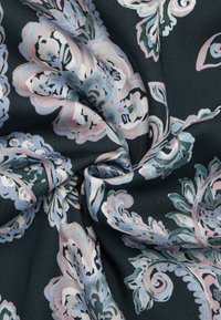 Tessuto scuro con un motivo floreale paisley in tonalità di rosa, blu e bianco, caratterizzato da intricati vortici e una texture liscia.
