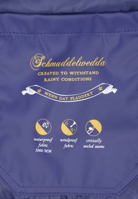 Zils ūdensizturīgs audums ar zelta tekstu. Ietver ikonas par ūdensizturību (3000 MM), vēja necaurlaidību un kritiski noslēgtām šuvēm.