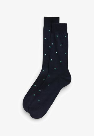 Calzini navy in tessuto morbido con un motivo di piccoli quadrati verdi distribuiti uniformemente. Cuffia a coste sulla parte superiore.