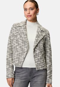 Gestreepte, zwart-witte tweed jas met een notch-kraag, slim fit en lange mouwen. G gedragen over een lichte, golvende hals trui.