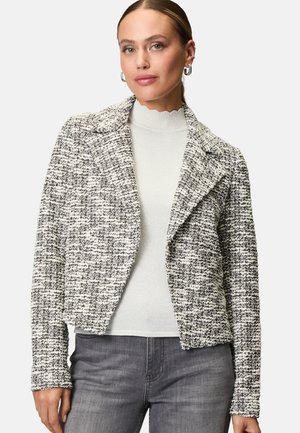 Gestreepte, zwart-witte tweed jas met een notch-kraag, slim fit en lange mouwen. G gedragen over een lichte, golvende hals trui.
