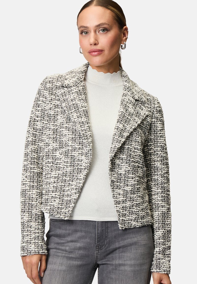 Gestreepte, zwart-witte tweed jas met een notch-kraag, slim fit en lange mouwen. G gedragen over een lichte, golvende hals trui.