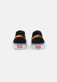 Baskets noires et orange en suède et toile, design bas, semelle en caoutchouc blanche, et logo Vans rouge sur le talon.