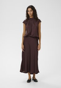 Bordový dvojdielny outfit s krátkym rukávom, plisovaným topom a zodpovedajúcou dlhú sukňou, oboje zdobené malými bielymi bodkami.