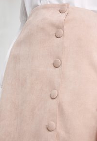 Ljusrosa, mockafodral kjol med en rad av fem runda knappar framtill. Slät textur med subtil lyster och skräddarsydd form.