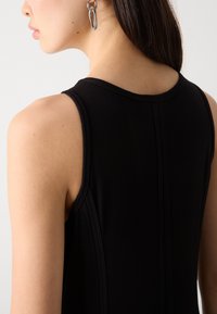 Top aderente nero con scollo rotondo e spalline sottili, dotato di cuciture visibili sul retro.