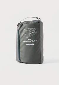 Συμπαγές γκρι νεσεσέρ με φερμουάρ και λαβή, με ετικέτα "40L Black Hole Duffel Patagonia", που περιέχει μια διπλωμένη σακούλα duffel.