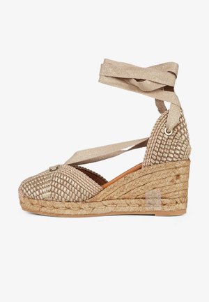 Sandalo espadrillas beige con zeppa intrecciata, lacci da avvolgere alla caviglia e suola platforma in juta intrecciata.