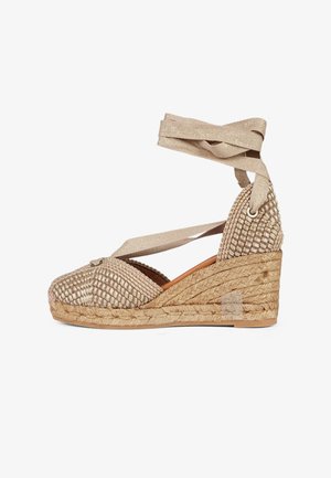 Sandalo espadrillas beige con zeppa intrecciata, lacci da avvolgere alla caviglia e suola platforma in juta intrecciata.