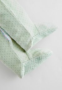 Grønne plyssandaler med en prikket tekstur, spids tå og blomstrede for. Blødt materiale med accentdetaljer på sålen.