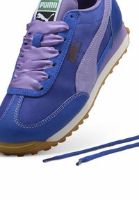 Sininen ja violetti Puma Easy Rider -urheilukenkä, jossa on satiiniväylät, nahka- ja kankaamateriaaleja, teksturoitu kumipohja ja brändäys.