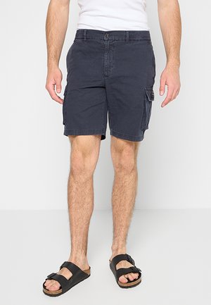 Shorts cargo navy en coton avec une coupe décontractée, comportant des poches latérales et une fermeture à bouton, associés à des sandales noires.