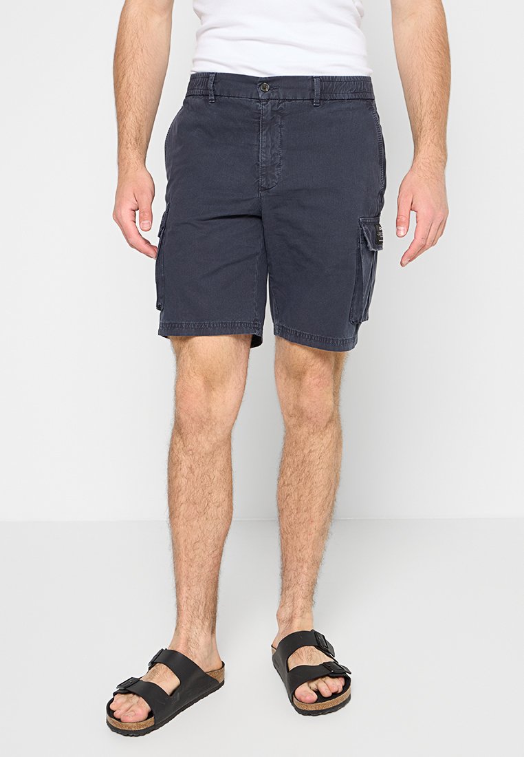 Shorts cargo navy en coton avec une coupe décontractée, comportant des poches latérales et une fermeture à bouton, associés à des sandales noires.