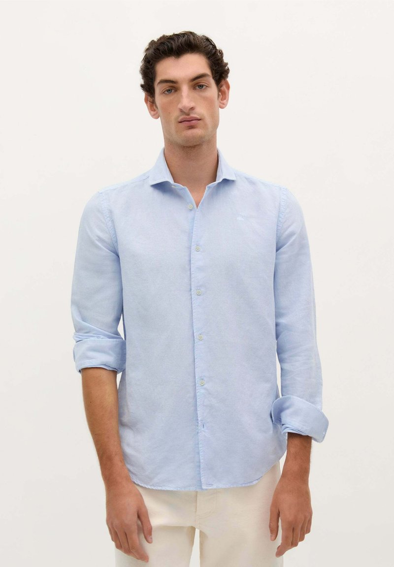 Camicetta azzurro chiaro button-up realizzata in un tessuto morbido. Presenta un colletto classico, maniche lunghe arrotolate ai polsini e dettagli di cucitura sottili.