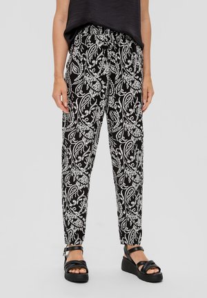 Zwart-wit gebloemde broek met een taillekoord, gedragen met zwarte platformsandalen en een zwart mouwloos topje.