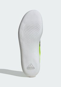 Biely gumový povrch tenisky s textúrovaným vzorom malých pyramíd, s logom adidas, doplnený jasne zelenými stranami.