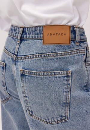 Jasnoniebieskie dżinsy z wysokim stanem, z dwoma tylnymi kieszeniami oraz wytłoczonym brązowym skórzanym metkiem z napisem "ANATAKA".