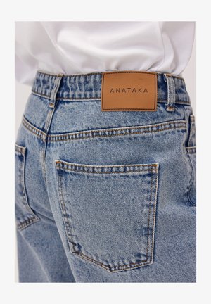 Jasnoniebieskie dżinsy z wysokim stanem, z dwoma tylnymi kieszeniami oraz wytłoczonym brązowym skórzanym metkiem z napisem "ANATAKA".