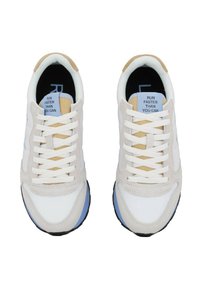 Baskets blanches et gris clair avec des accents bleus, en tissu et en daim, avec des lacets plats et une étiquette de langue beige avec du texte.