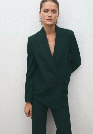 Ciemnozielony, dopasowany garnitur dwurzędowy z klapami i dwoma przednimi kieszeniami. Gładki materiał o strukturalnym kroju i kontrastowe guziki.