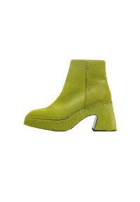 Botas de tobillo de pelaje verde con un tacón grueso y acampanado y suela con plataforma. Textura suave, diseño curvado y detalle de suela negra contrastante.
