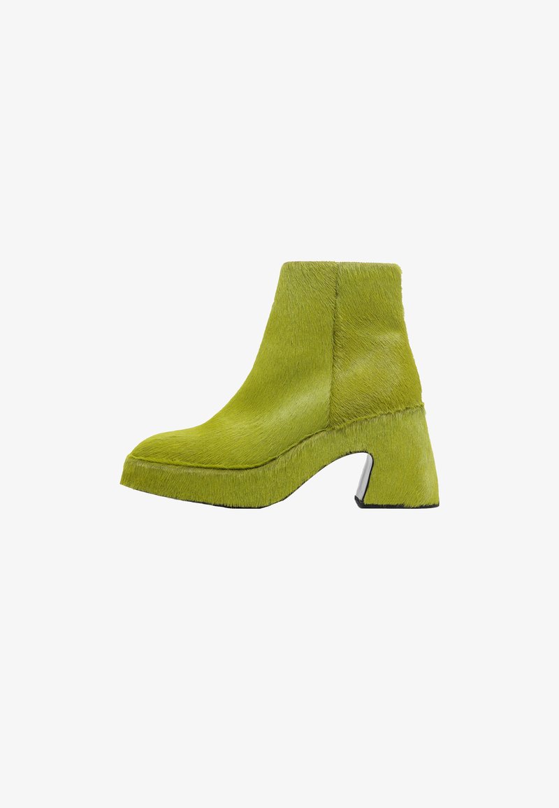 Botas de tobillo de pelaje verde con un tacón grueso y acampanado y suela con plataforma. Textura suave, diseño curvado y detalle de suela negra contrastante.