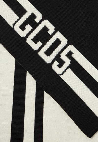 Pulover din tricot cu textură netedă, în negru și crem, având un logo îndrăzneț "GCDS" și dungi verticale; culori și modele contrastante.