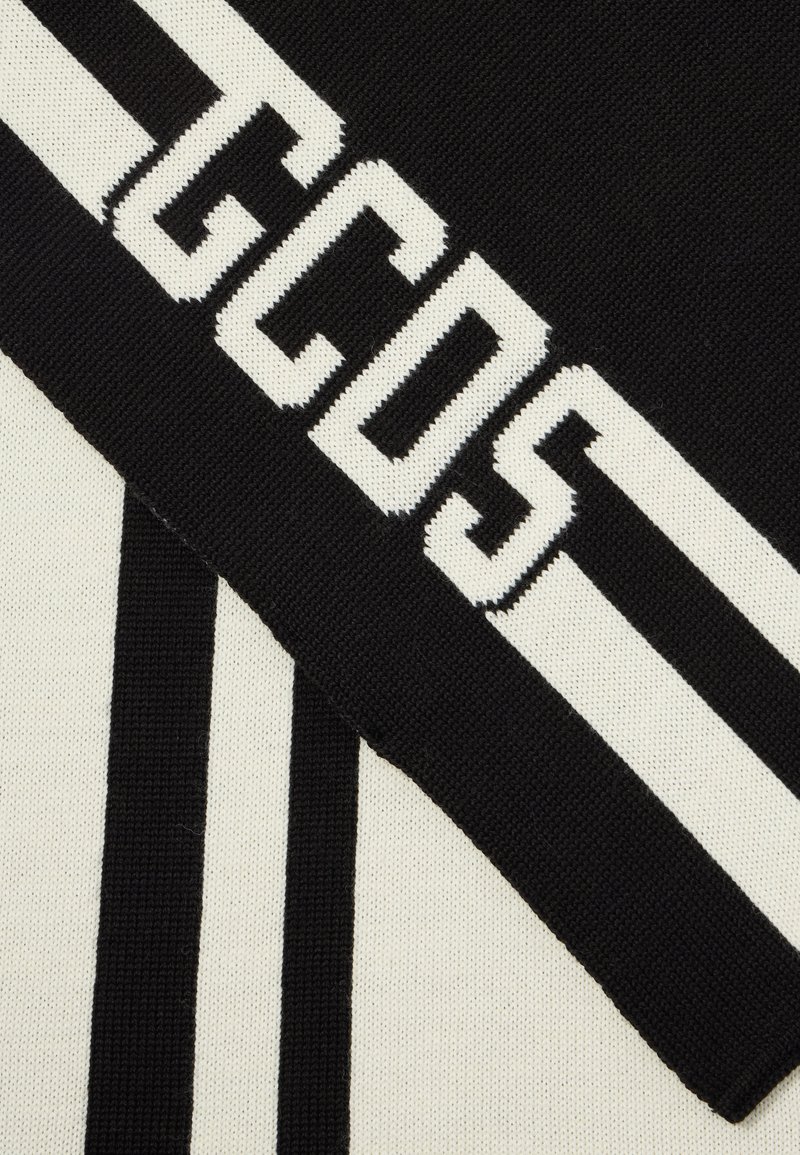 Strickpullover aus schwarzem und cremefarbenem Stoff mit boldem "GCDS"-Logo und vertikalen Streifen; glatte Textur mit kontrastierenden Farben und Mustern.