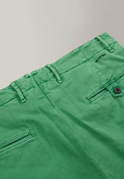 Los pantalones cortos de algodón verdes cuentan con una cinturilla plana con trabillas, botón de cierre y bolsillos traseros con detalles de costura sutil.