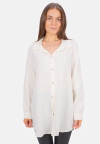 White button-up shirt made of textured, lightweight fabric; features a collar, long sleeves, and a loose fit with a hem that curves slightly.