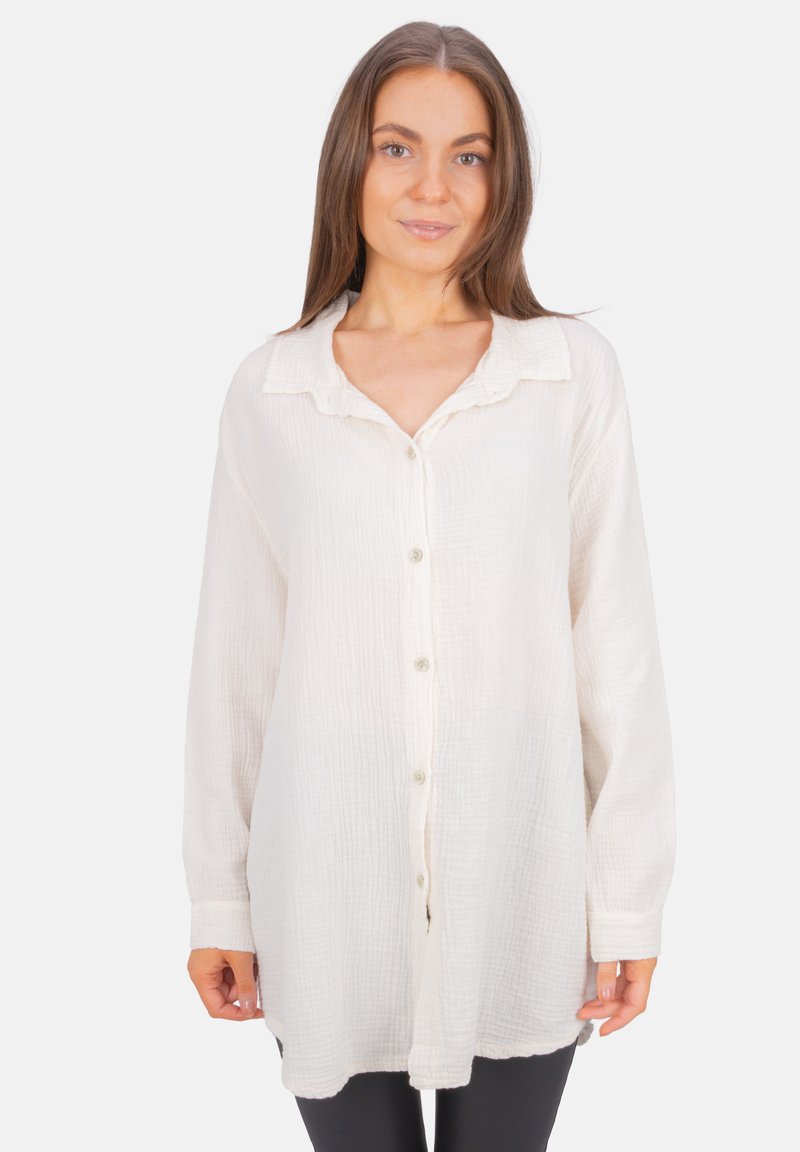 White button-up shirt made of textured, lightweight fabric; features a collar, long sleeves, and a loose fit with a hem that curves slightly.