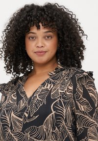 Blusa preta com padrão de folhas bege, decote em v e detalhes franzidos nos ombros. Tecido leve e texturizado com um design fluido.