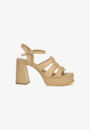 Sandales à plateforme beige avec de larges brides croisées, fermoir ajustable à la cheville et un talon épais. Texture lisse et lignes épurées.