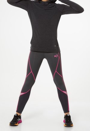 Maglietta nera a maniche lunghe con cappuccio abbinata a leggings grigi con accenti geometrici rosa; entrambi realizzati in tessuto tecnico elastico.