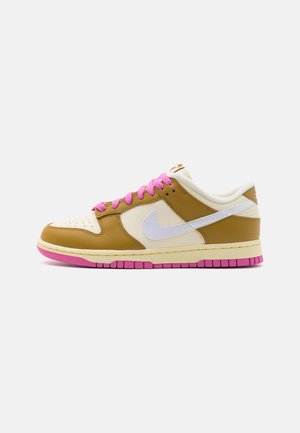 Low-top sneaker with tan and cream panels, white Nike swoosh, pink laces, and pink outsole on a white background, shown in side profile.