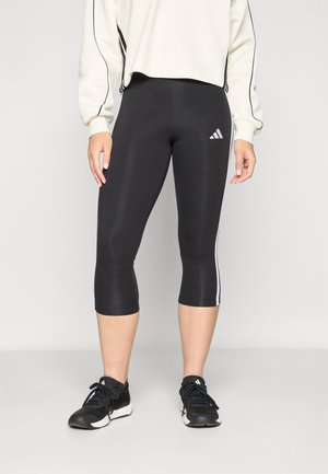 Leggings neri a vita alta realizzati in materiale elasticizzato, con strisce laterali bianche e logo Adidas sulla coscia sinistra.