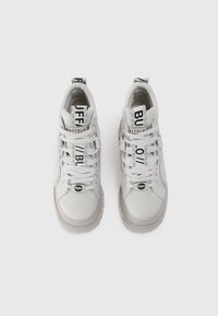 Valkoiset korkeavartiset tennarit, jotka on valmistettu sileästä materiaalista, jossa on teksturoitu kärki. Ominaisuuksiin kuuluvat litteät nauhat, logo mustalla tarralla ja paksut pohjat.