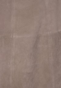 Mikrofaser in sanftem Mauve, mit einer glatten Textur und sichtbaren Nähten sowie Paneelen, die ein subtil geometrisches Muster bilden.