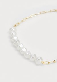 Collana in oro con perle bianche irregolari, dalla superficie liscia e lucida. Ogni perla presenta lievi variazioni nella forma e nelle dimensioni.