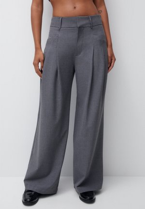 Pantalones gris de pierna ancha con pliegues frontales, textura suave y un ajuste entallado. Presentan una cinturilla plana y bolsillos laterales.
