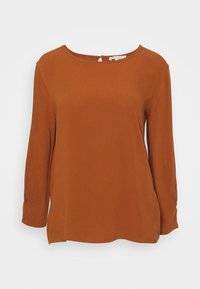 Top color ruggine con maniche lunghe e scollo a barca. Presenta una piccola chiusura a occhio di bue sul retro. Tessuto morbido, vestibilità comoda.