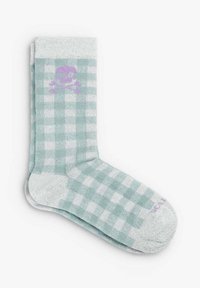 Calcetín a cuadros en tono azul claro y blanco, con una textura suave; presenta un diseño de calavera y tibias cruzadas en color púrpura en la parte delantera.