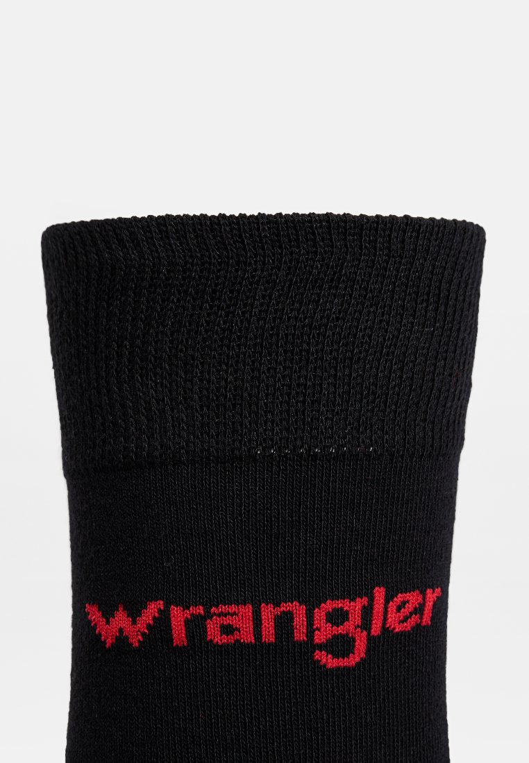 Czarna bawełniana skarpetka o prążkowanej fakturze, z czerwonym logo "Wrangler" na mankiecie. Projekt jest prosty i sięga do wysokości połowy łydki.
